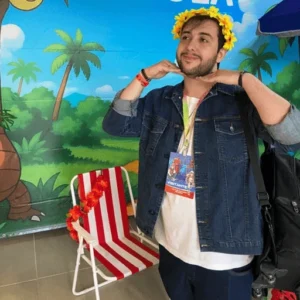 André “Cast” Bruni sorrindo com coroa de flores, num evento de cartas Pokémon